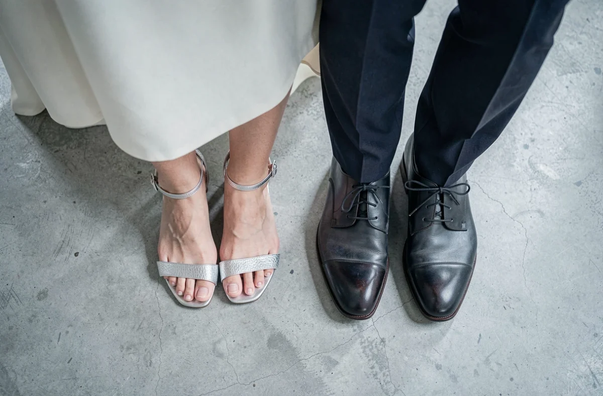 Vue du dessus de sandales argentées féminines et de chaussures masculines élégantes côte à côte lors d'une cérémonie de mariage civil moderne